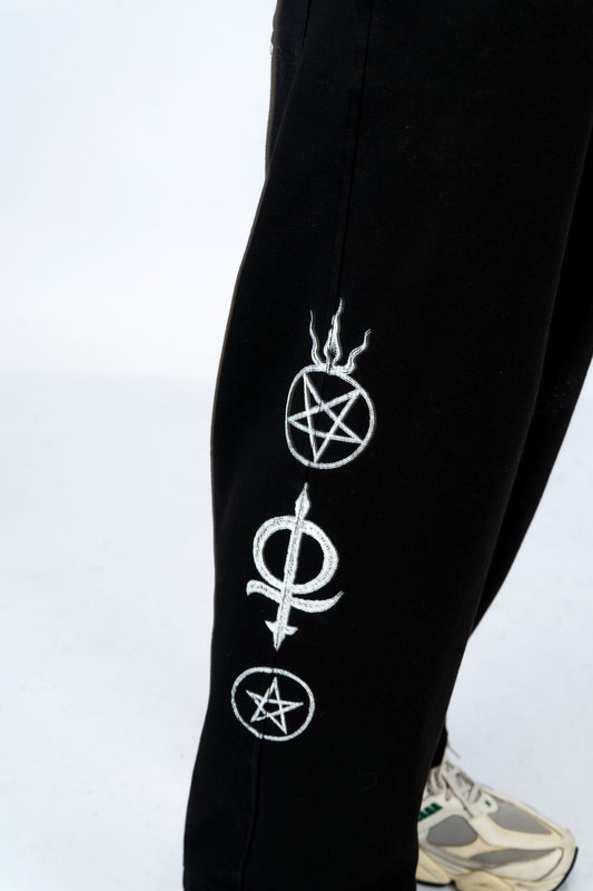 a person wearing a pair of black sweatpants with white symbols on them