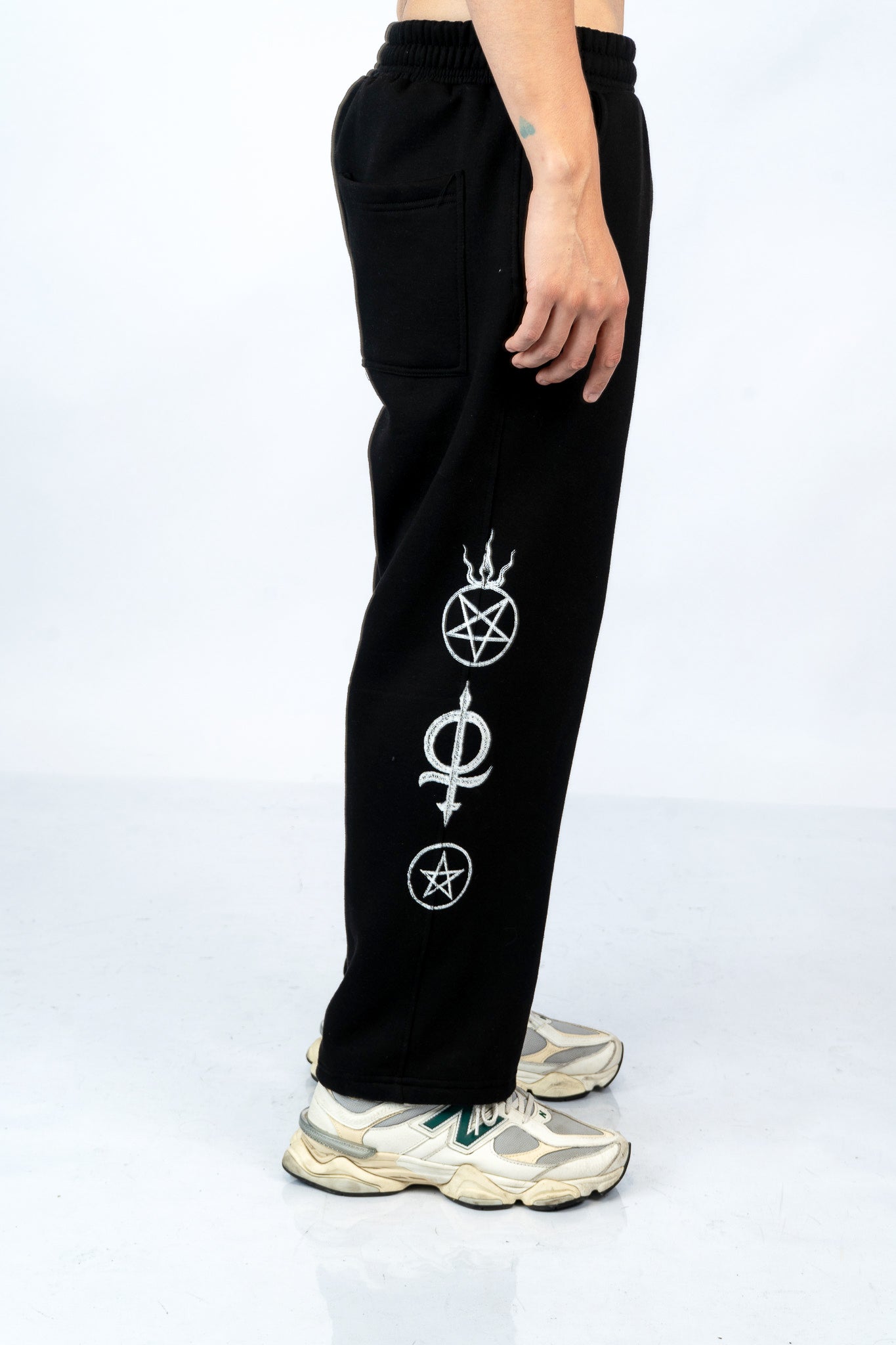 a person wearing a pair of black sweatpants with white symbols on them